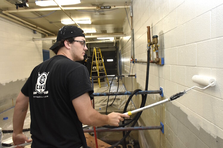 Josh Millikin paints a wall at The Rink.