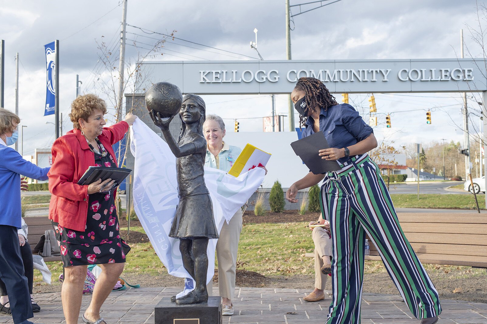 From left, Kay Calley-Martin and Kathy Shaw, co-chairs of the American Association of University Battle Creek Legacy Centennial Community Project Fund with Kellogg Community College President Dr. Adrien L. Bennings, unveil the statue, “Hope.”