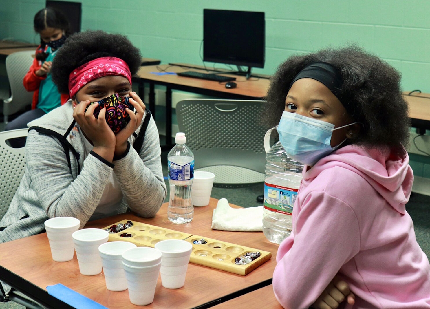 Two girls wear masks while playing games at the Boys & Girls Club.