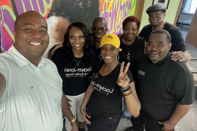 Arturo Puckerin, new executive director of the Kalamazoo Eastside Neighborhood Association, left, stands with Twala Locket-Jones, second from left, and members of her Realty group, after helping with a July food distribution event.