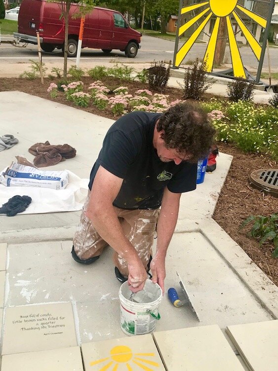 Artist Conrad Kaufman lays some final tiles at the Eastside Sunrise Plaza. 