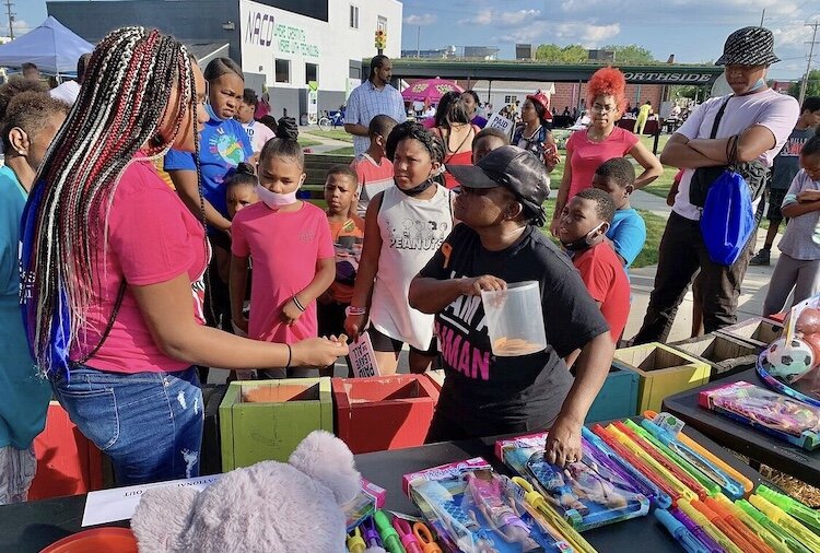 Mattie Jordan-Woods, executive director of the Northside Association for Community Development, at center in black, is shown presenting prizes to young people at the neighborhood’s 2021 National Night Out event.