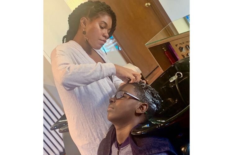 Lalonie Willhite, shown shampooing the hair of 12-year-old Emanuel Frye, learned how to style and cut hair when her foster parents did not know how.