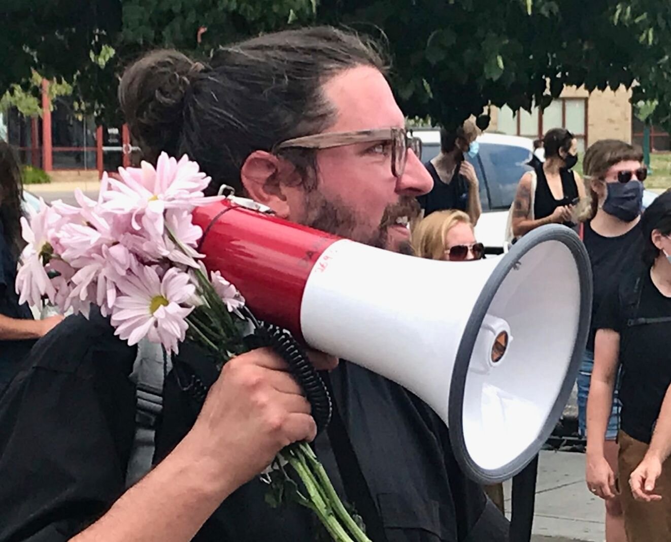 Using a megaphone adorned with the flowers, Rev. Nathan Dannison speaks to counter-protesters on Saturday, Aug. 15, 2020 in downtown Kalamazoo.