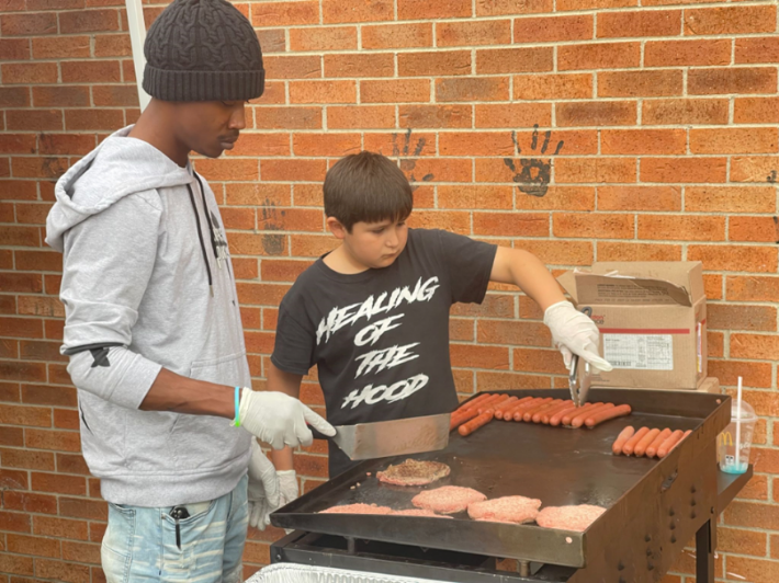 Montine “Mikey” Wiley jr., left, helps a youngster learn to cook.