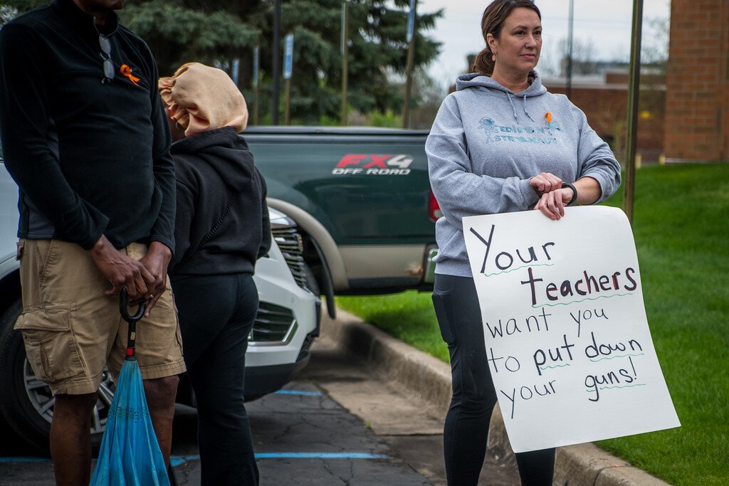 A woman holds an anti-gun violence sign at the start of the Wednesday, April 30, 2025 Dominion Walk in Kalamazoo.