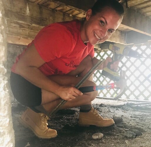 Katie McPherson, executive director of Building Blocks of Kalamazoo, is shown working beneath the porch of a house during a fix-up project in 2021.
