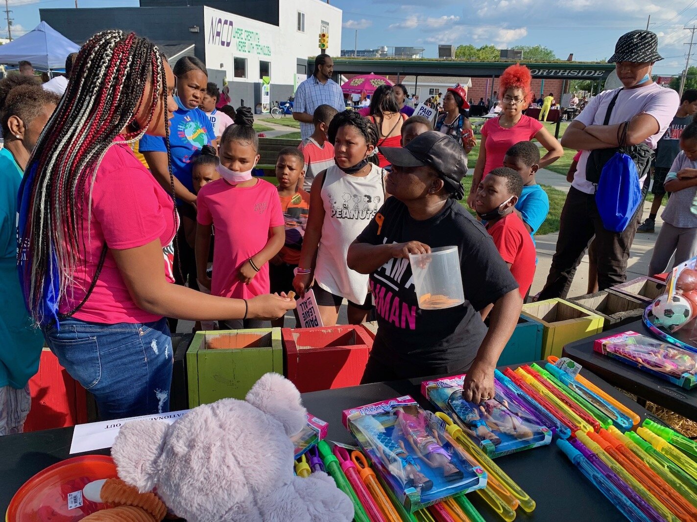 Maddie Jordan-Woods, center in black, helps with drawings for children’s toys during National Night Out.