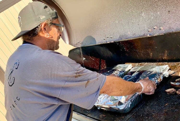 Ricky Thrash, who says he has been cooking for more than 45 years, keeps slabs of spare ribs warm on the grill behind Bone Yard Café.