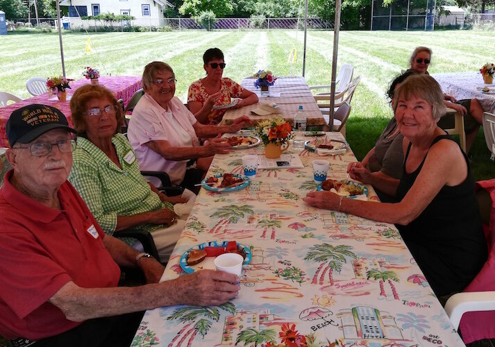 A group of people enjoy a conversation at the 2019 Oakwood Neighborhood Reunion. Among them, at left in the white shirt, is Pat Henry, author of a history of the Oakwood Neighborhood.