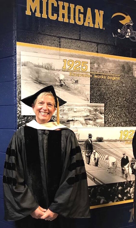 University of Michigan graduate Jeanne Hess is shown in 2017 representing the faculty of Kalamazoo College at the 200th commencement of the U-M. She is standing in a tunnel inside Michigan Stadium.