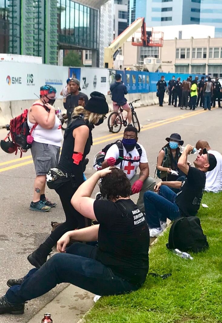 Several people get water as treatment for pepper spray adjacent to the Arcadia Creek fest place in downtown Kalamazoo.