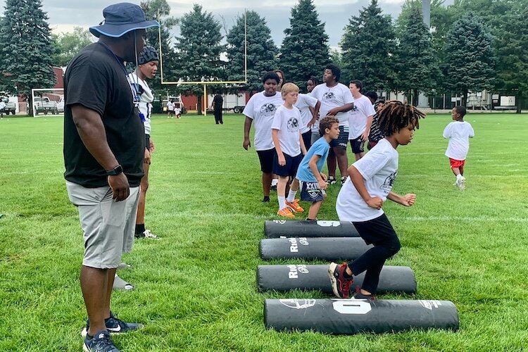 A young football player spreads his arm as he prepares to do a long jump during the Kalamazoo Youth Football Camp, held Saturday, Aug. 26, 2025 at Mayor’s Riverfront Park.