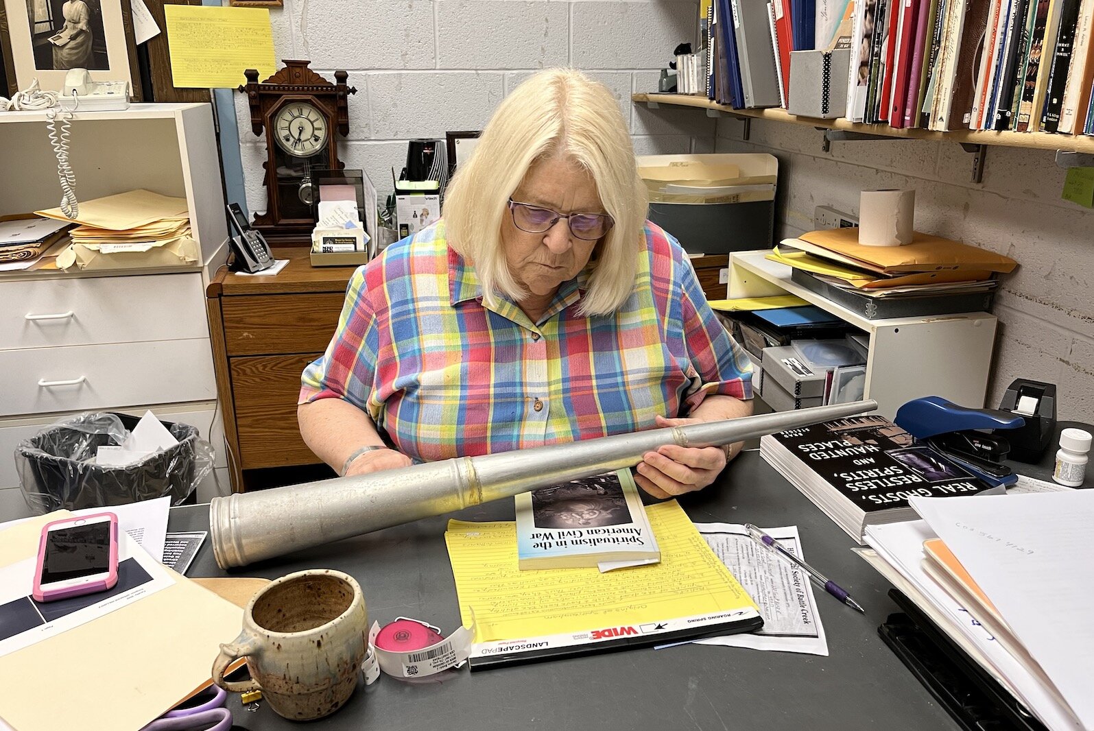 Jody Owens, a volunteer with the Battle Creek Historical Society, looks at a Spirit Trumpet that is part of the Historical Society's collection. Spirit trumpets were used to magnify the whispers of the spirits.