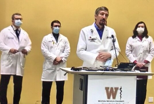 Dr. Aaron Lane-Davies of Bronson Healthcare Group, at the podium, was among a group of physicians to urge people to become vaccinated during a special Dec. 7 press conference at W-Med. 