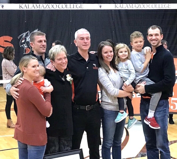 At her final game as head volleyball coach at Kalamazoo College, Oct. 28, 2018, Jeanne Hess is surrounded by family. See the full description below.