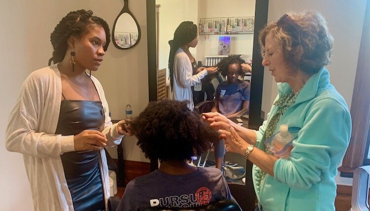 Lalonie Willhite, left, discusses proper care for textured hair with Sara Frye. In the middle is Frye’s daughter Grace.