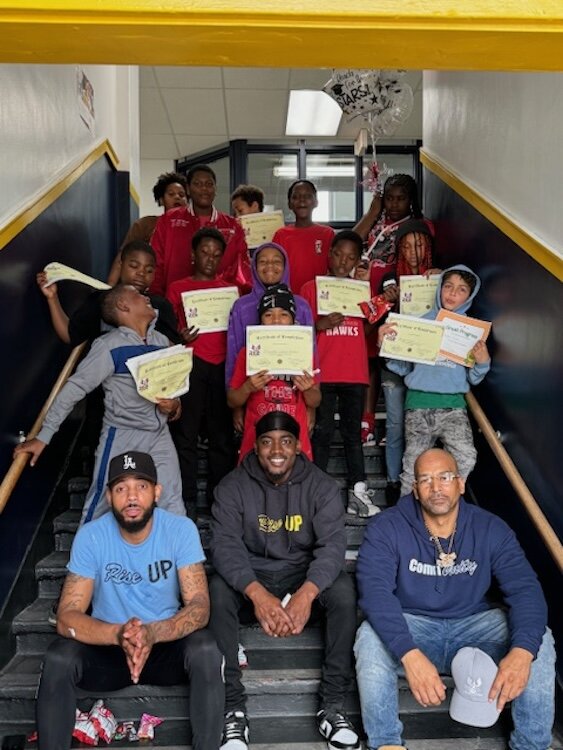 Kaypree Taylor, left front, celebrates the achievements of youth who participated in programming offered by R.I.S.E., with an unidentified R.I.S.E. staff member, center, and Damon Brown, founder of the organization.