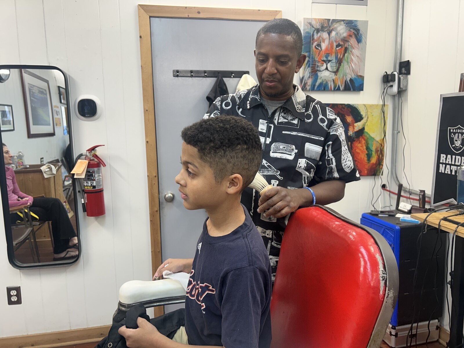 David Lehman-Oliver, 9, gets his haircut by his longtime barber Jerome Lenzy at Rob’s Barber Shop during a Barbershop and Literacy event in the Vine Neighborhood.