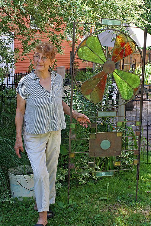 Jane Schelhas poses in her yard with one of her creations.