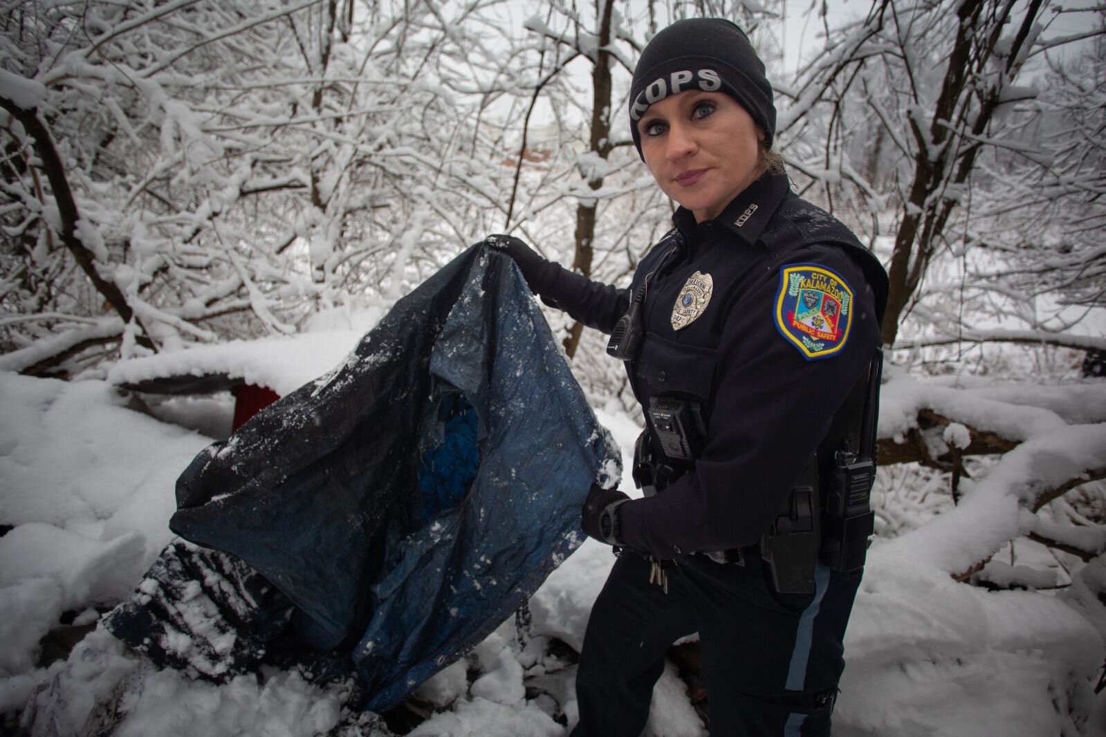 Kalamazoo Public Safety Officer Mary Miller looks at refuse left at a site where unhoused people camped. 