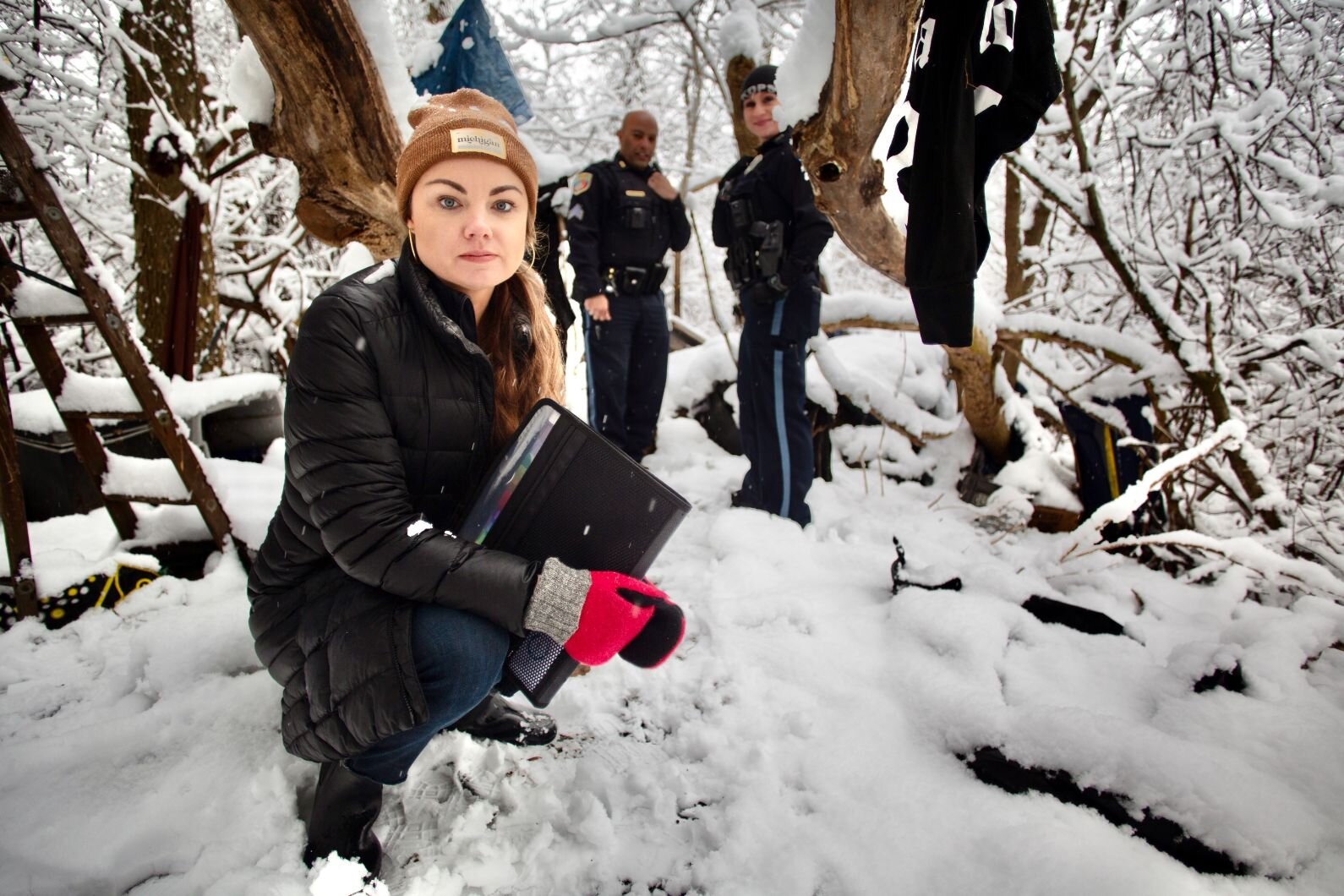 Kelsey Harness, social services coordinator for Kalamazoo Public Safety's new Community Service Team, looks around a wooded area where unhoused people  camped until recently on the city's Eastside.