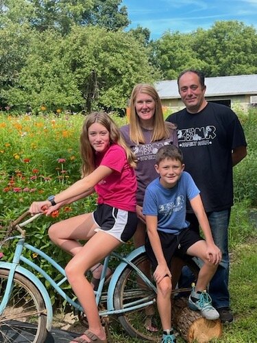 Ella Laupp, on bike, with her mom and dad, Rebekah and Mike, at right, and her brother, Zack, front and center. The bike has been added to their gardens for use by visitors as a photo opportunity.