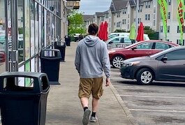 A man walks casually along a row of Campus Pointe Mall businesses on Monday, May 8, 2023. The area has been plagued in recent months with gun violence and weekend visitors who loiter in their cars.