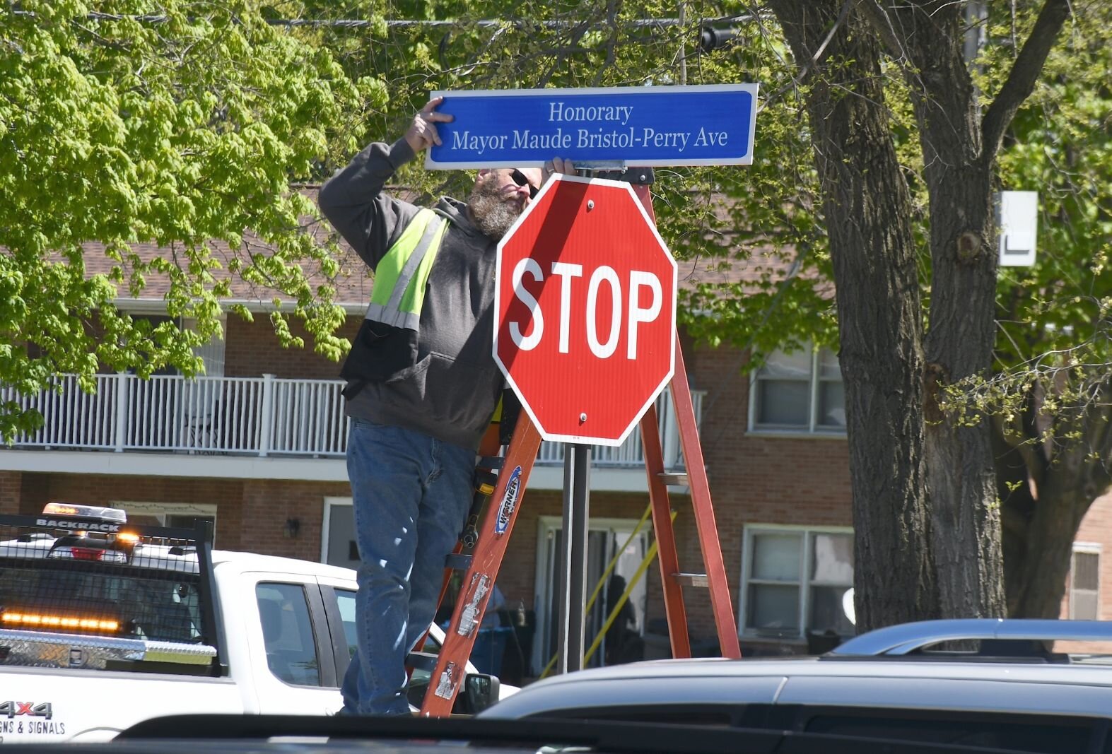 Joe Wright of the City of Battle Creek puts up the sign unveiling Honorary Mayor Maude Bristol-Perry Avenue.