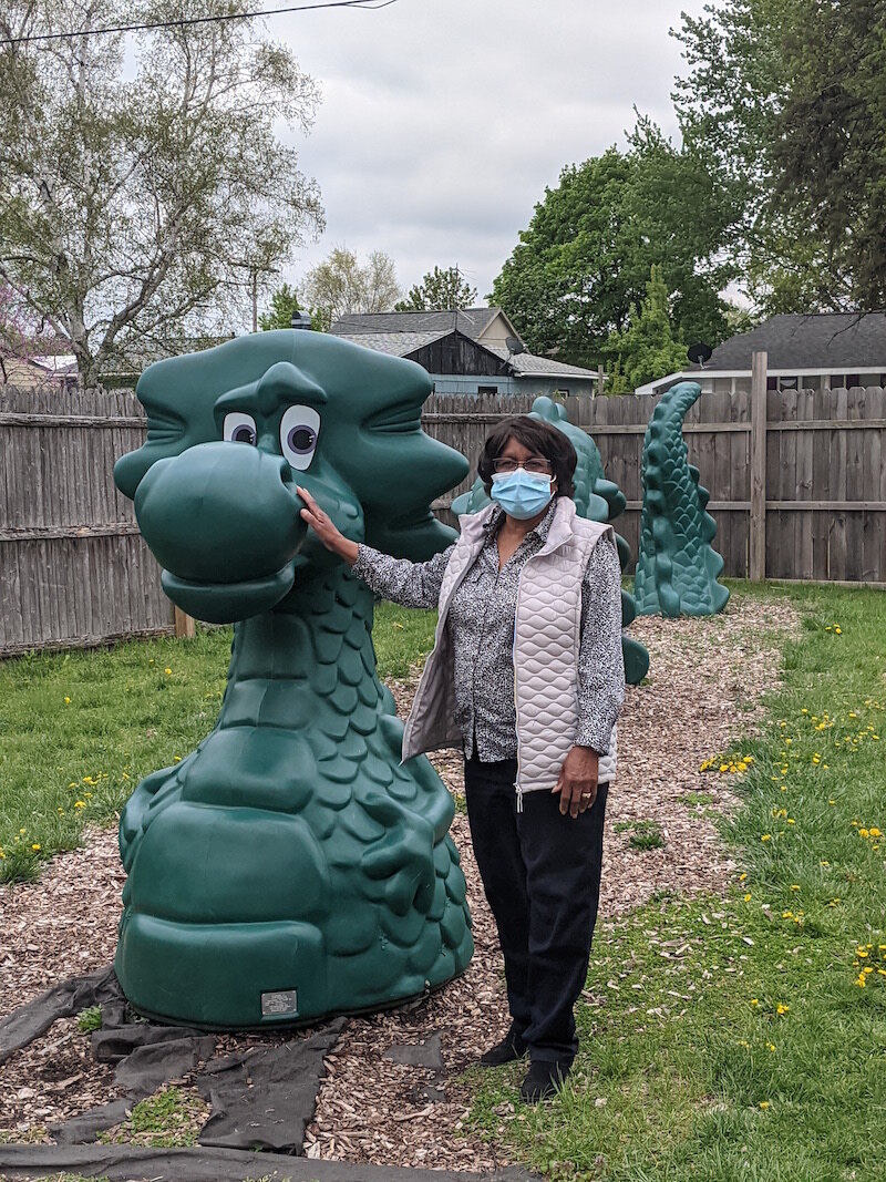 Maude Bristol-Perry, owner of Sugar and Spice Childcare Center, poses with a dragon that is among a wide variety of playground equipment in the backyard of the center.
