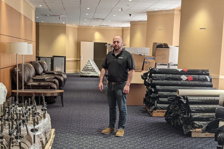 Joe Sobieralski, President and CEO of Battle Creek Unlimited, stands in a hallway on the hotel's ground floor flanked by rolls of carpeting and other items that were available for purchase beginning on April 14 as part of an ongoing liquidation sale.