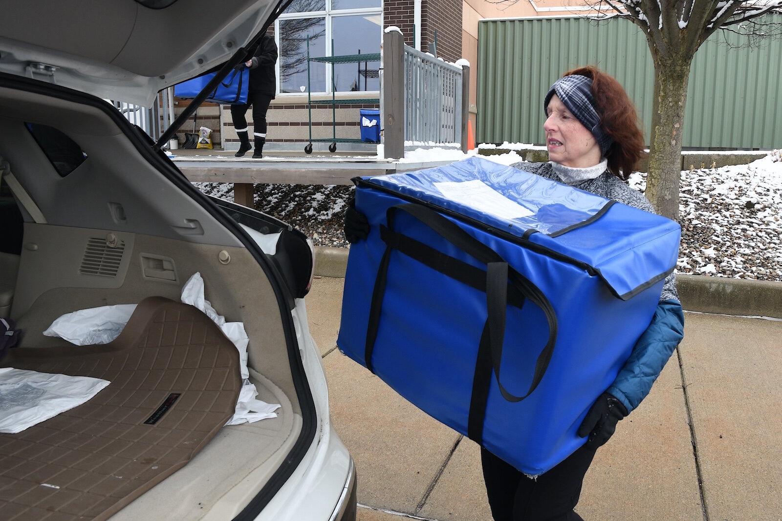 Theresa Burke loads up meals to be delivered into her vehicle.