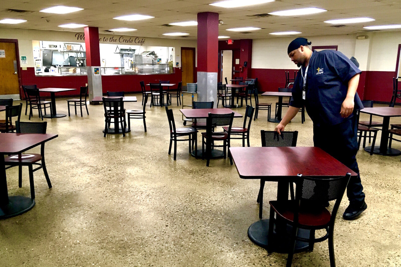 Brian Carpenter, a cafeteria supervisor, sets up chairs for dinner on a recent afternoon at the Kalamazoo Gospel Mission. The mission has removed about half of the tables from its cafeteria.