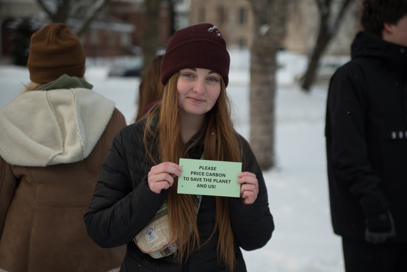 Activist Mia Breznau holds a snowperson sign calling on government to price carbon, a vital step in addressing climate changing and safeguarding her future