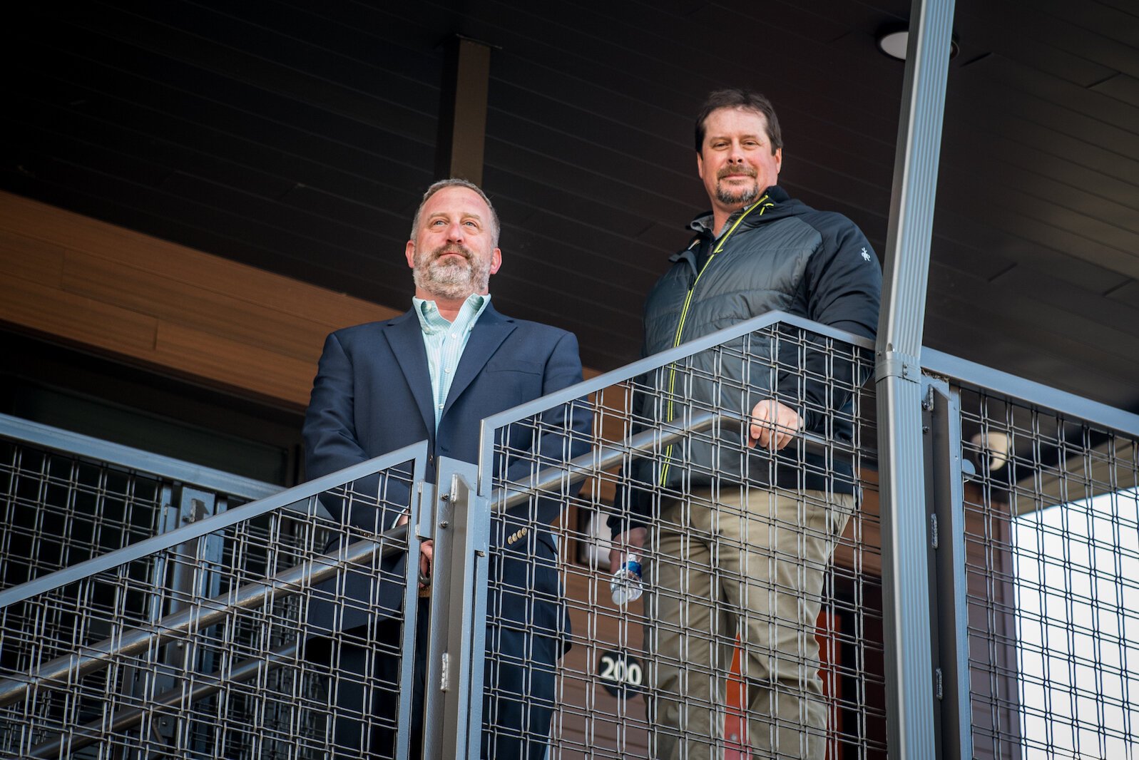 Josh Rohs, left, director of Communication and Guidance for construction management firm CSM Group, stands on the exterior balcony of LodgeHouse with Todd George, project managers for the LodgeHodge redevelopment. 