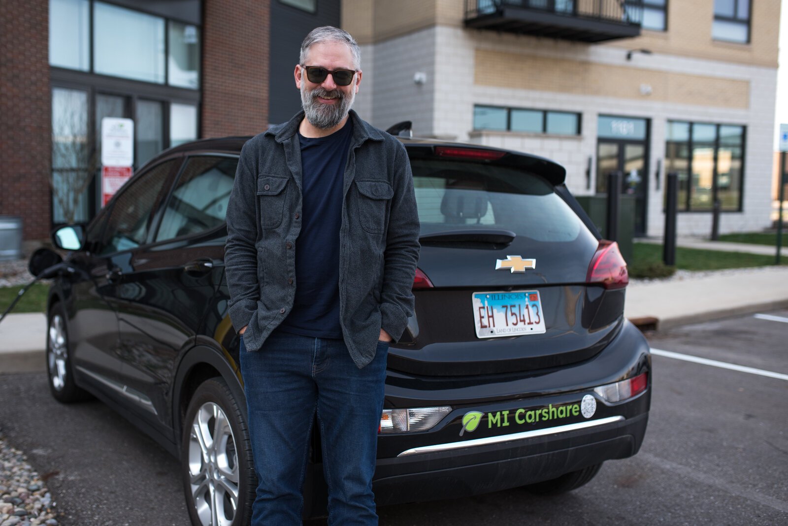 Matthew Hollander of Hollander Development Corporation stands near the Carshare Chevrolet Bolt at The Creamery.