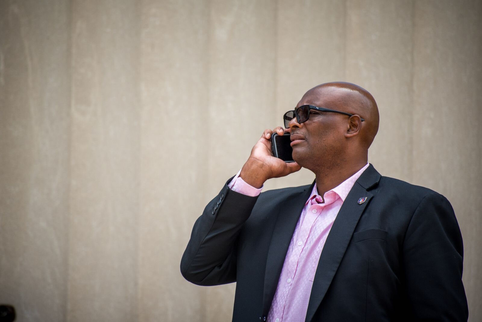 Department of Public Safety Chief Vernon Coakley Jr. takes a call as squad car sirens sound a block away from a press conference in front of Kalamazoo City Hall to announce a $400 million donation to the Foundation for Excellence.