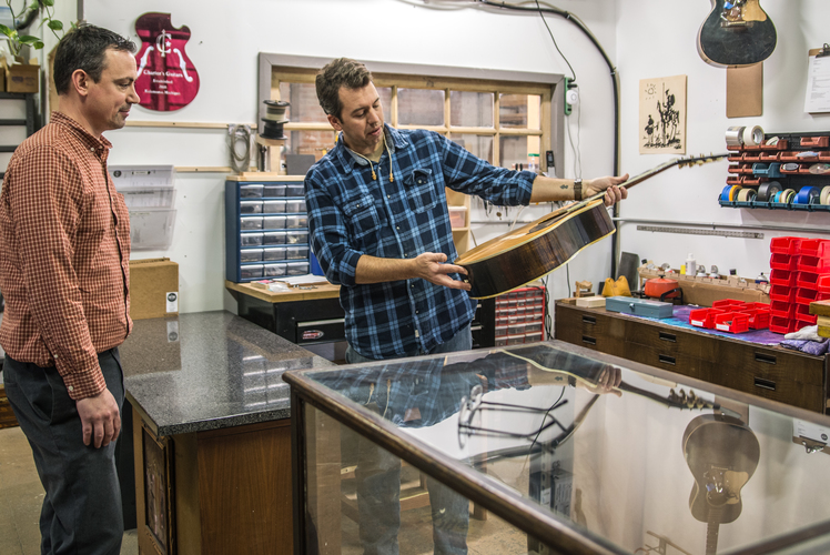 Chris Brown, grandson of Gibson Guitar designer Hartford Sider, picks up a guitar from Ry Charters. 