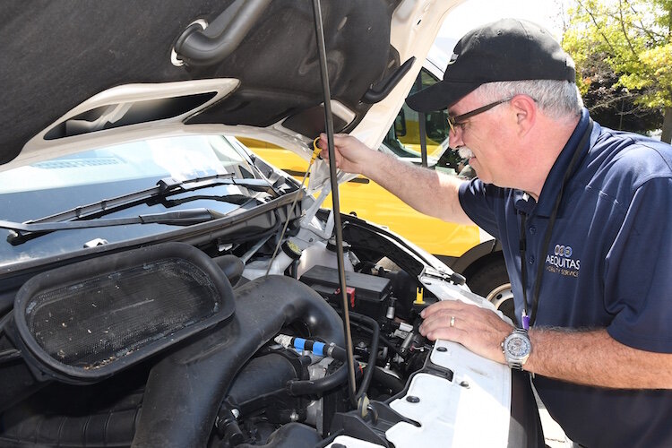 Randy Padgett, a driver for Aequitas Mobility Services, checks the fluid of one the organization’s vehicles. 