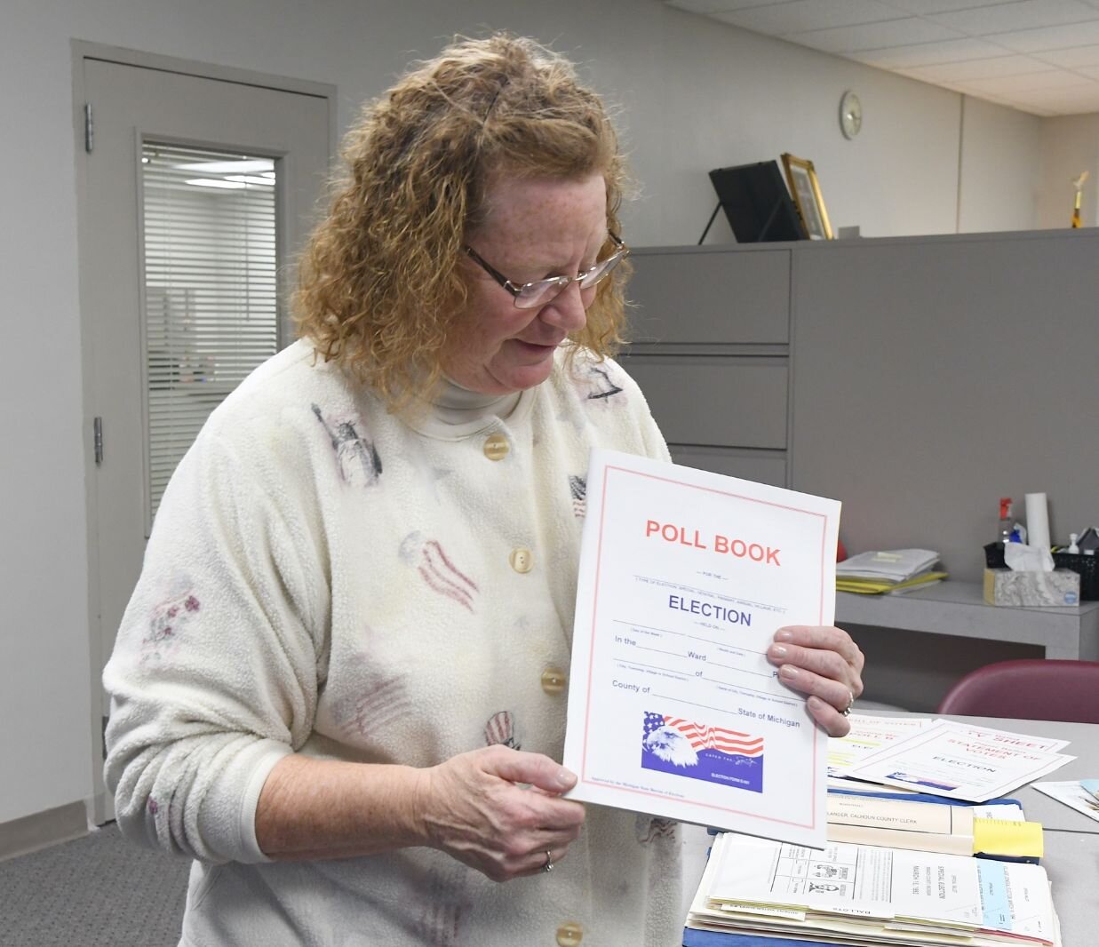 Teri Loew, Chief Deputy Clerk of Elections for Calhoun County, holds up a polling book.