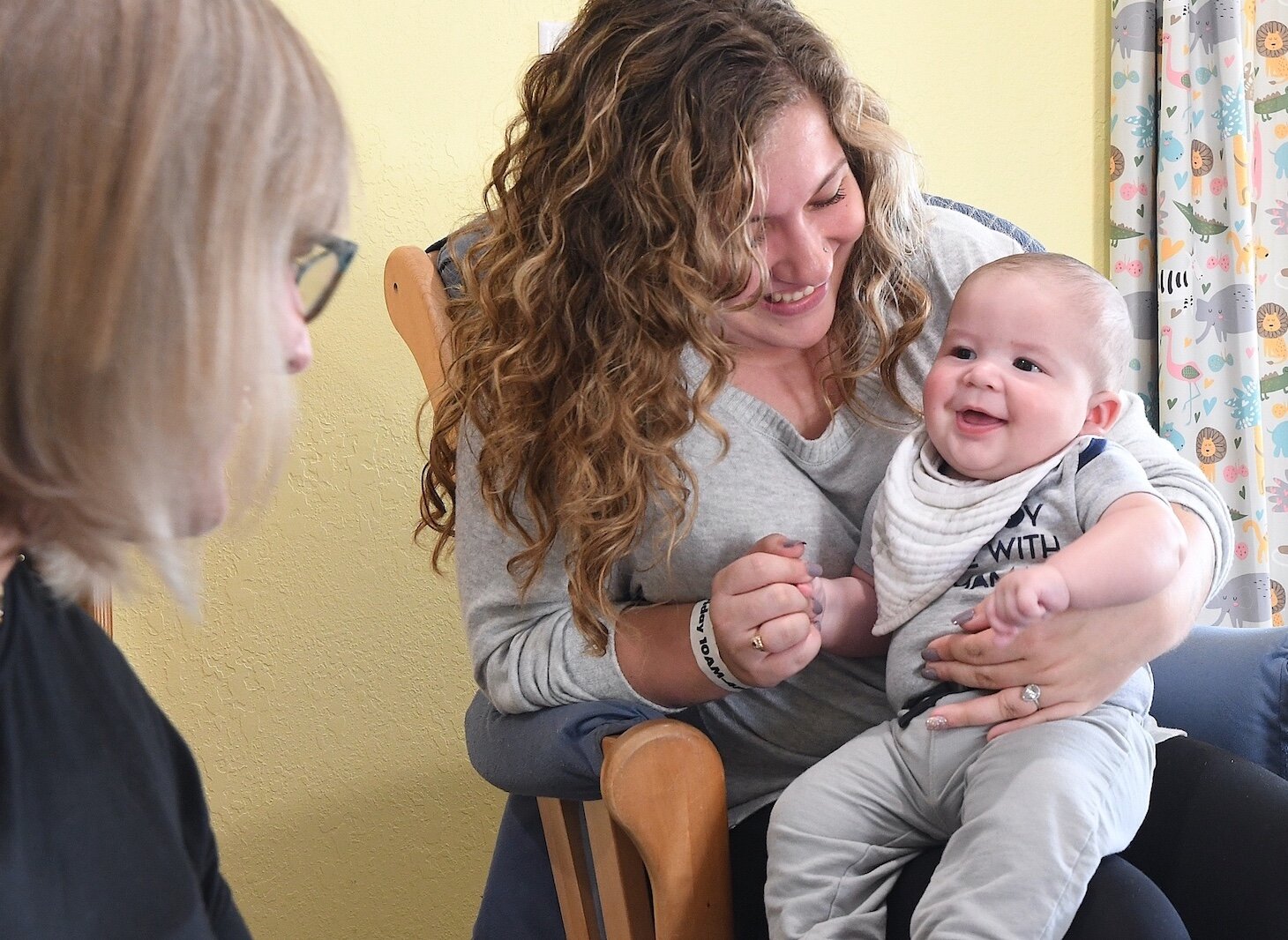 Stacey Olsen tries to get the attention of Nathan Cook, being held by Skylee Kosarue at Rose of Sharon Child Development Center.