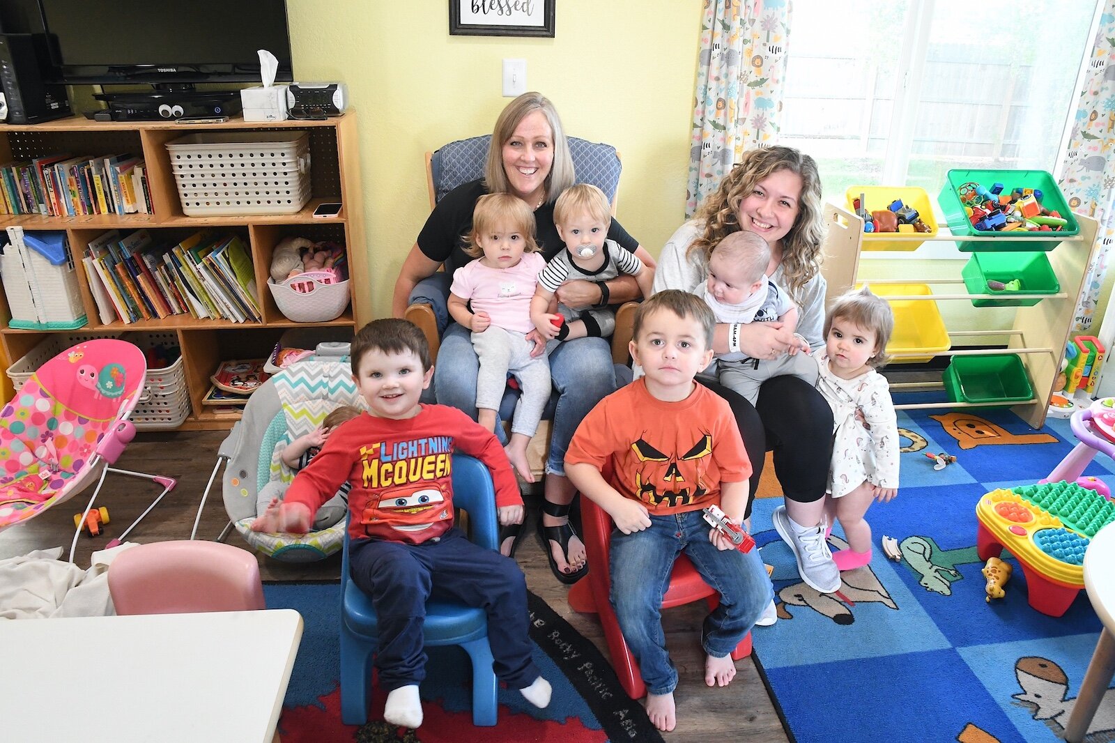 Stacey Olsen in the back and Skylee Kosarue are seen with children at Rose of Sharon Child Development Center.