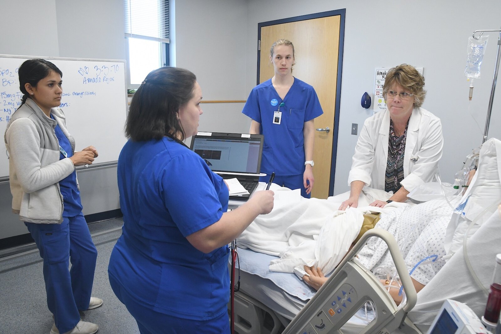 Renee Mielke, Ed.D., KCC nursing professor, talks with students about their treatment of a patient.