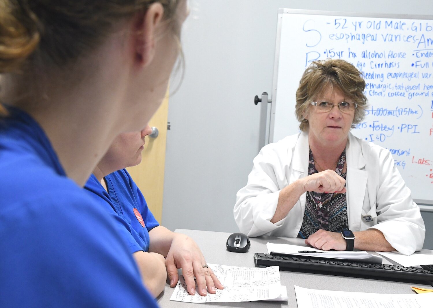 Renee Mielke, Ed.D., KCC nursing professor, talks with students about their treatment of a patient.