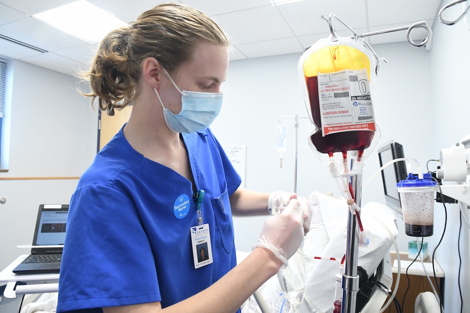 Caleb Vander Weide, a Kellogg Community College nursing student, adjusts the blood transfusion bag for “patient” Amado Rojos in the college’s sim lab.