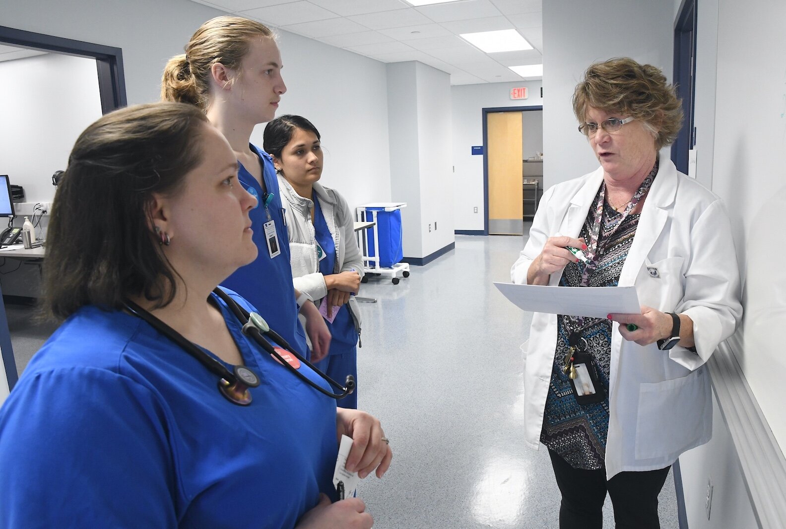 Renee Mielke, Ed.D., KCC nursing professor, talks with students about their treatment of a patient.