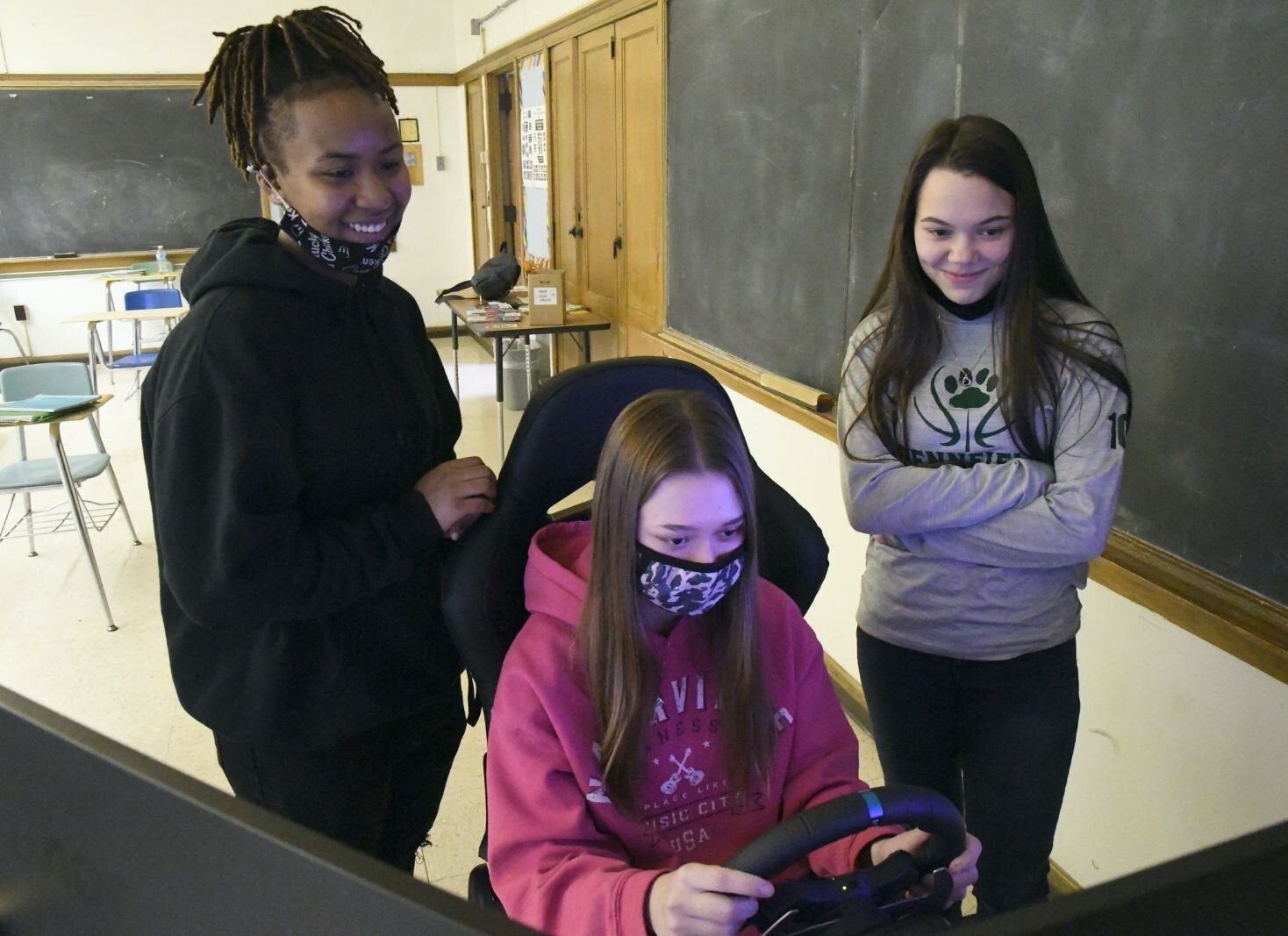 NyMir Pettis, left, and Jasmine Curtis, right, watch Brittney Wiley practice driving on a simulator in a driver education/training class at Kingdom Builders Worldwide.