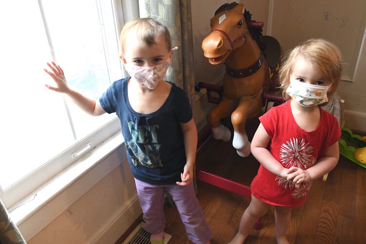 Aveline Potier, 4, left, and her sister Melina, 2, stand next to a window that was recently replaced In their family’s home.