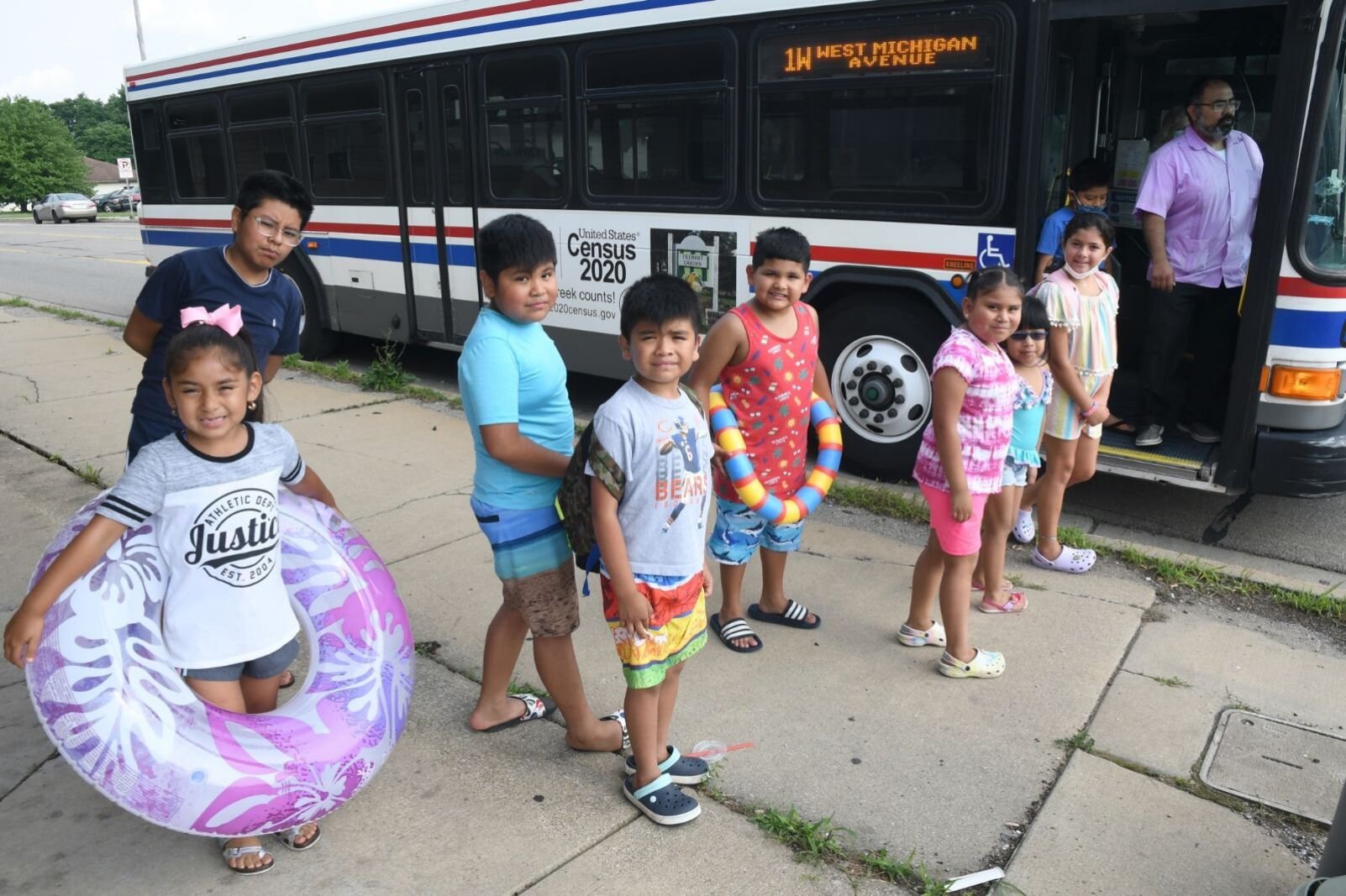 Jose Orozco, executive director of VOCES, and a group of children prepare to board a Battle Creek city bus to go to Full Blast.