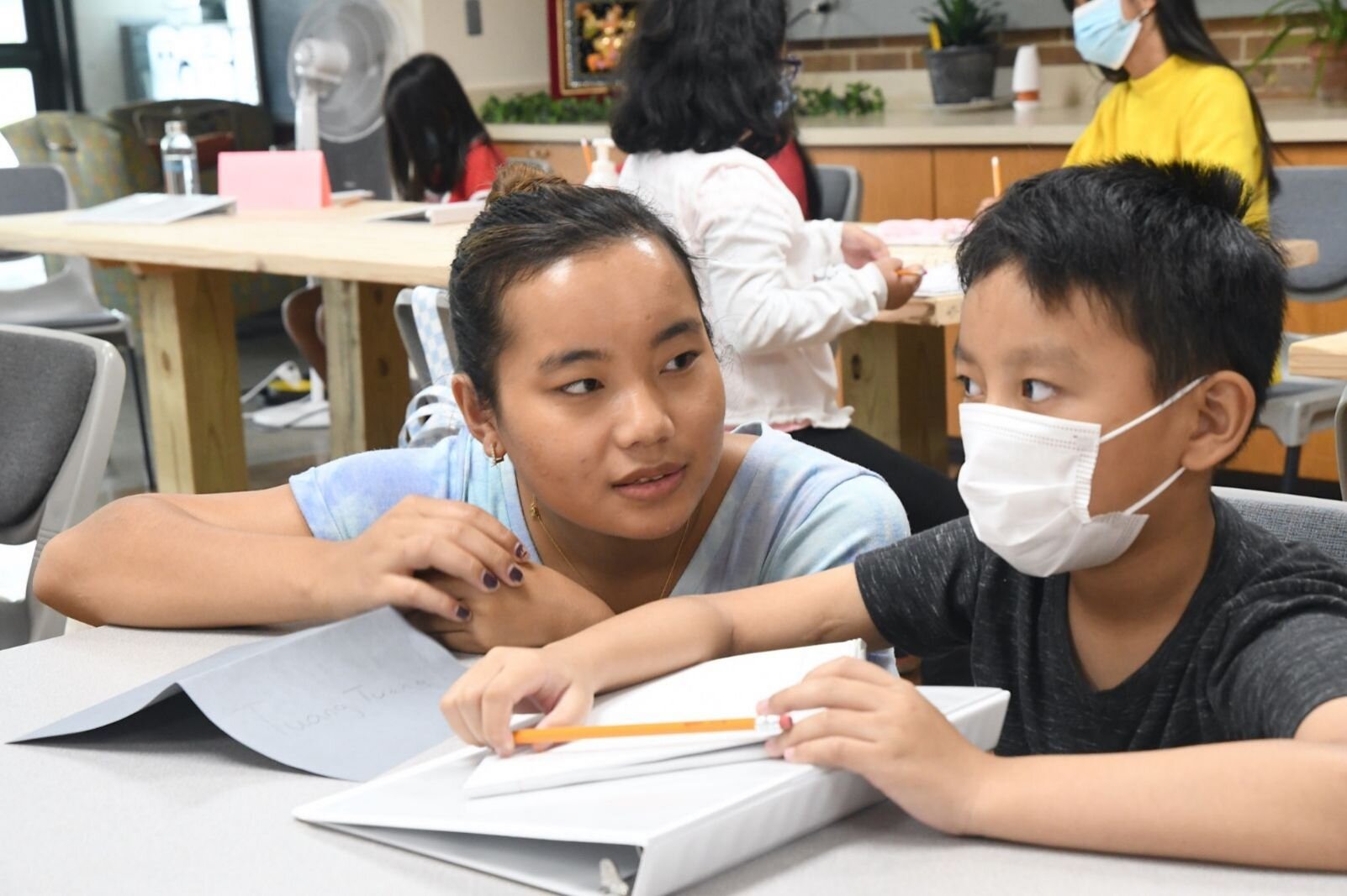 Teacher Dawt Par works with student Klup Tuang, 9, during a summer school session at the Burma Center.